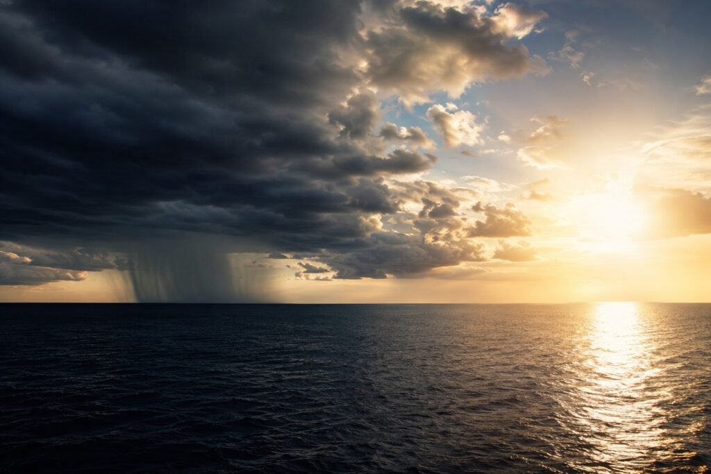 Vista aérea do Oceano Pacífico com contraste entre nuvens de tempestade e áreas ensolaradas, representando as variações climáticas.